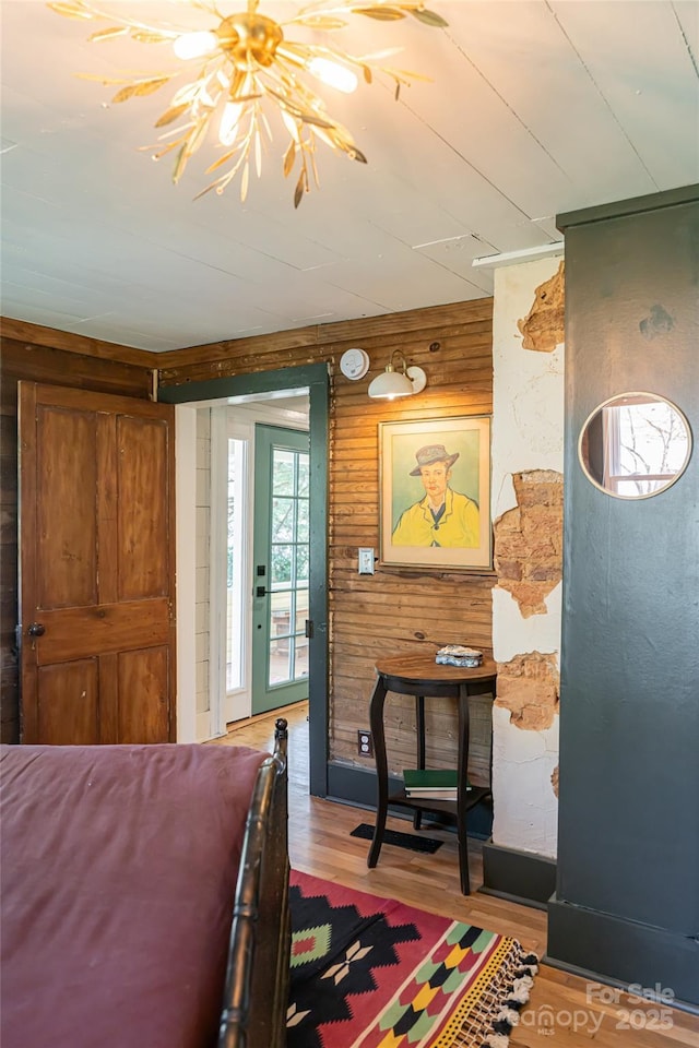 bedroom with access to exterior, wood walls, and wood finished floors