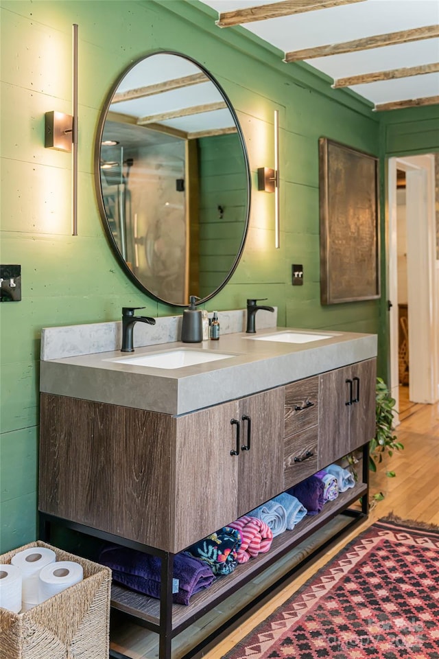 bathroom with double vanity, wood finished floors, and a sink