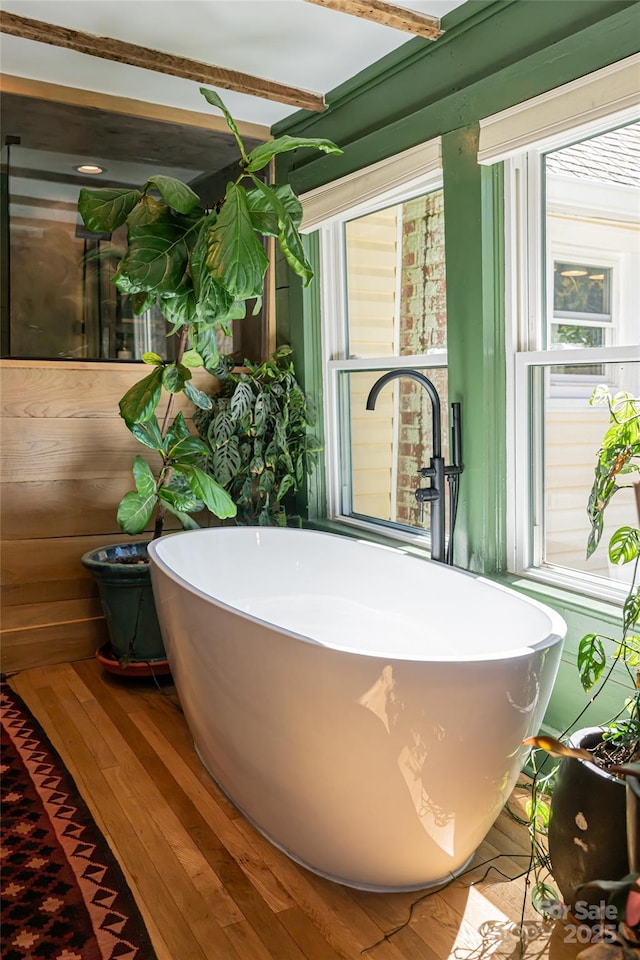 details with a sink, a soaking tub, and wood finished floors