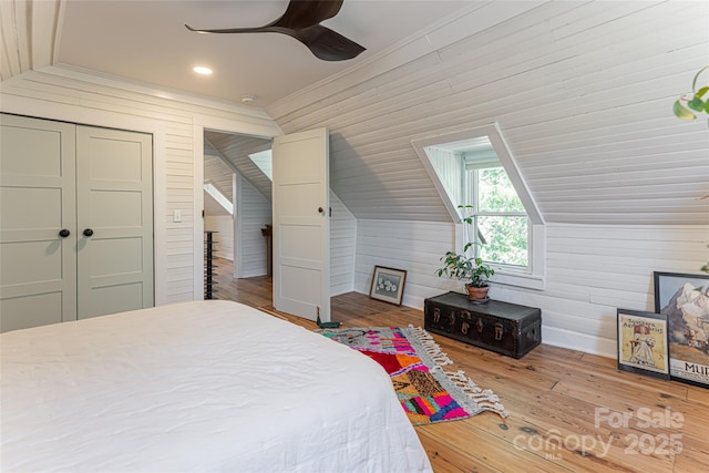 bedroom with wood walls, wood finished floors, crown molding, and vaulted ceiling