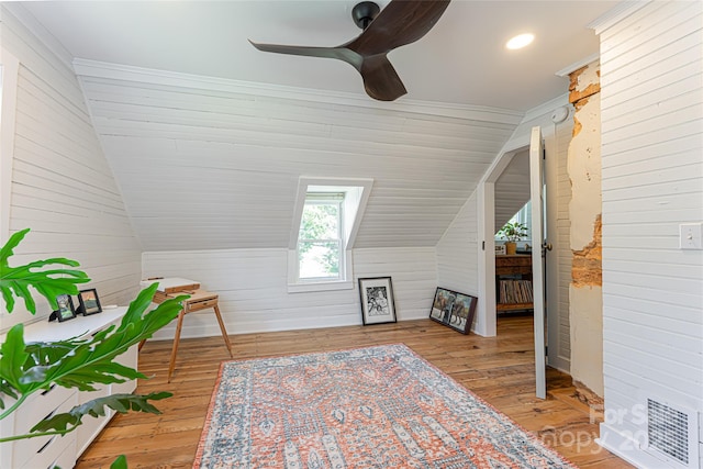 additional living space with lofted ceiling, wood walls, a ceiling fan, and hardwood / wood-style flooring