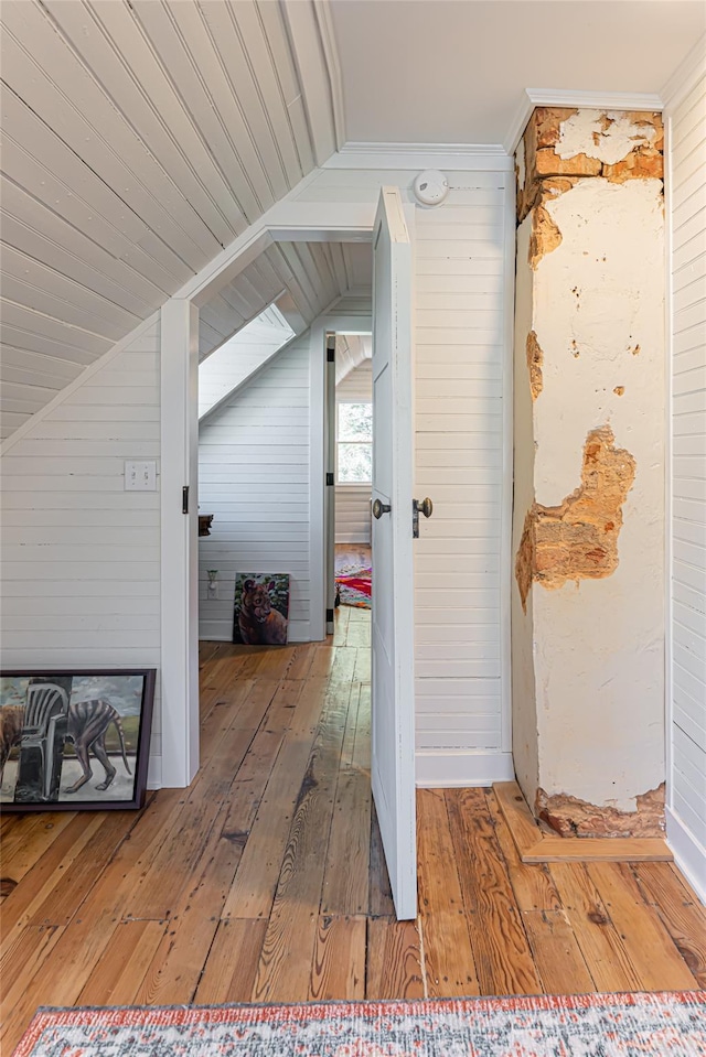 interior space with vaulted ceiling, wooden walls, and hardwood / wood-style flooring