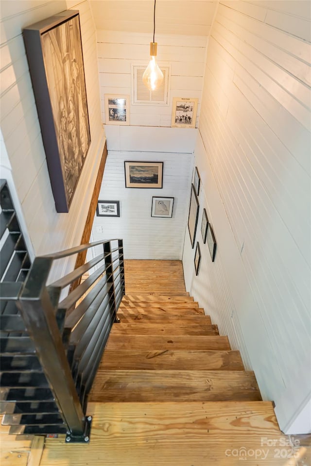 staircase featuring wooden walls and wood finished floors