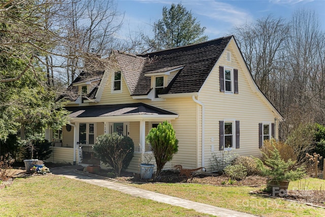 view of front of house featuring a chimney, roof with shingles, a porch, and a front lawn