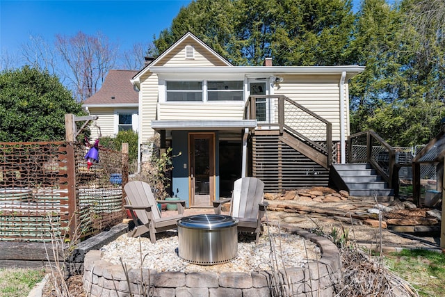 back of property with a chimney, stairway, and an outdoor fire pit