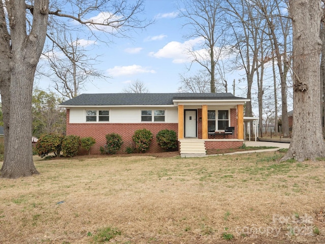 view of front of home with covered porch, brick siding, and a front yard