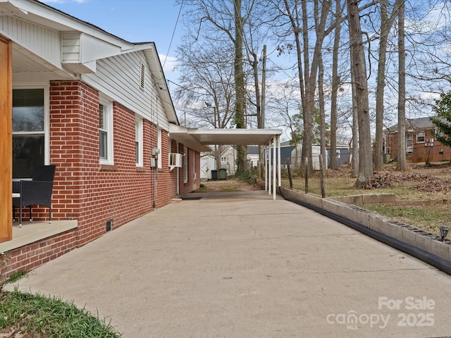 view of home's exterior with concrete driveway, brick siding, cooling unit, and an attached carport