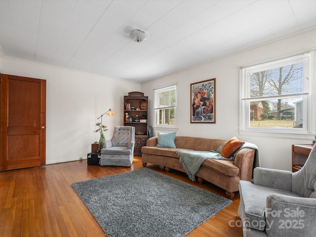 living room featuring hardwood / wood-style flooring, baseboards, and crown molding