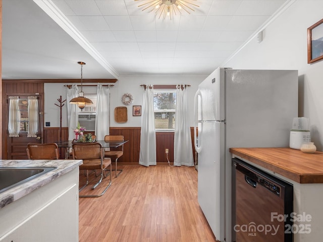 kitchen with light wood-style flooring, butcher block countertops, ornamental molding, wainscoting, and dishwasher