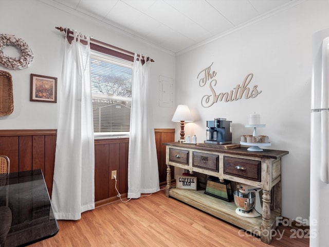 living area with a wainscoted wall, wooden walls, ornamental molding, and wood finished floors