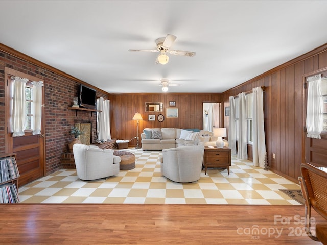 living room featuring ceiling fan, wood walls, a fireplace, and tile patterned floors