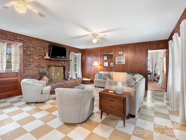 living area featuring a fireplace, ceiling fan, wood walls, and light floors