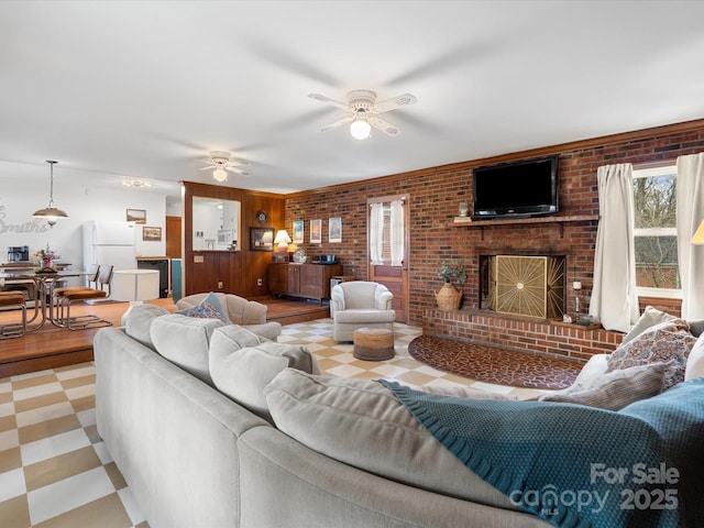 living room featuring brick wall, a brick fireplace, a ceiling fan, and tile patterned floors