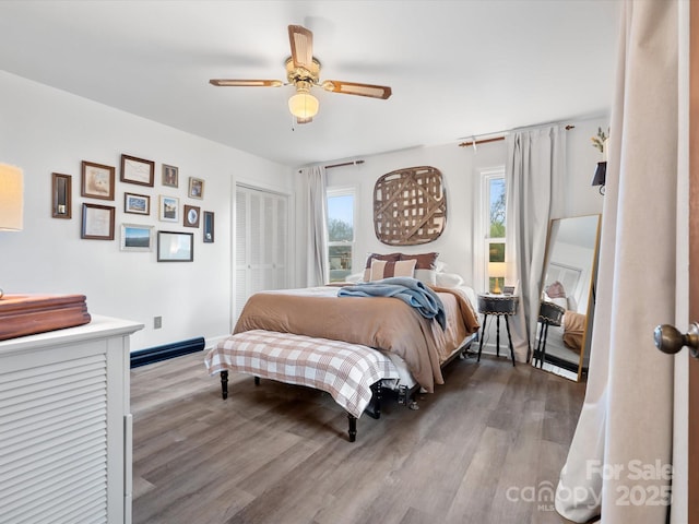 bedroom with a closet, ceiling fan, baseboards, and wood finished floors