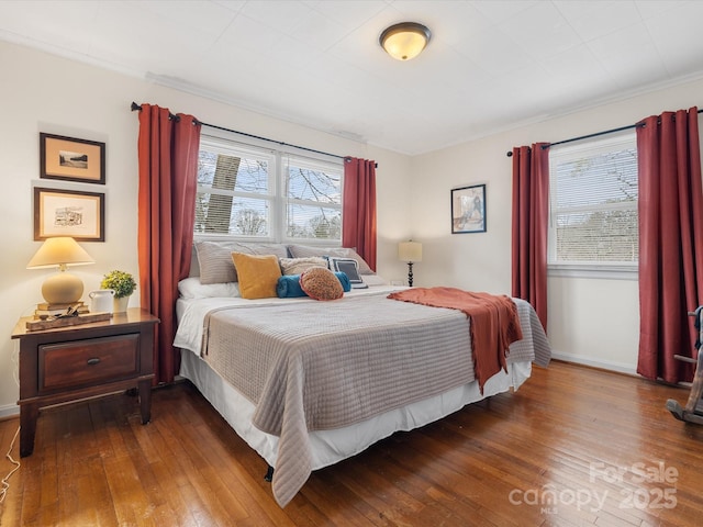 bedroom with baseboards, crown molding, and hardwood / wood-style floors