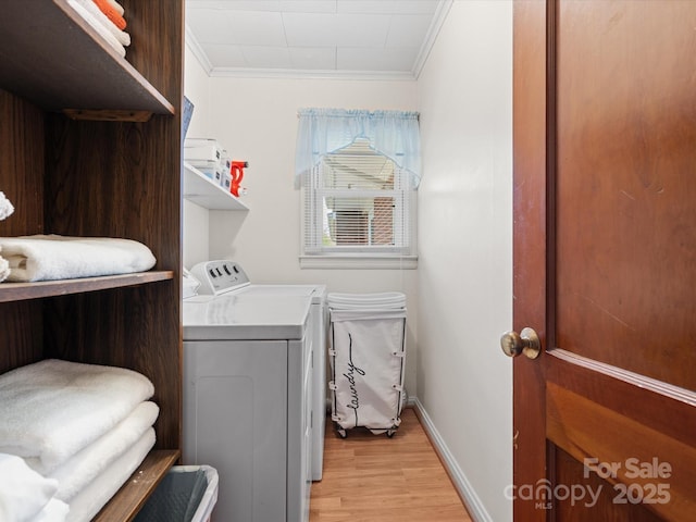 clothes washing area featuring laundry area, baseboards, ornamental molding, light wood-type flooring, and separate washer and dryer