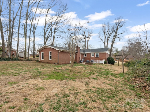 rear view of property with brick siding, a yard, and a chimney