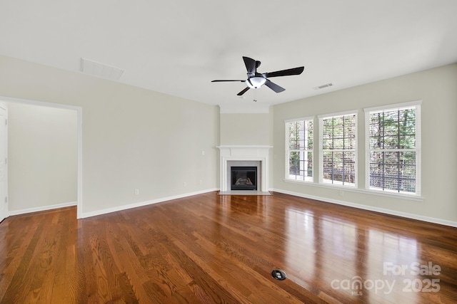 unfurnished living room featuring visible vents, a fireplace with flush hearth, baseboards, and wood finished floors