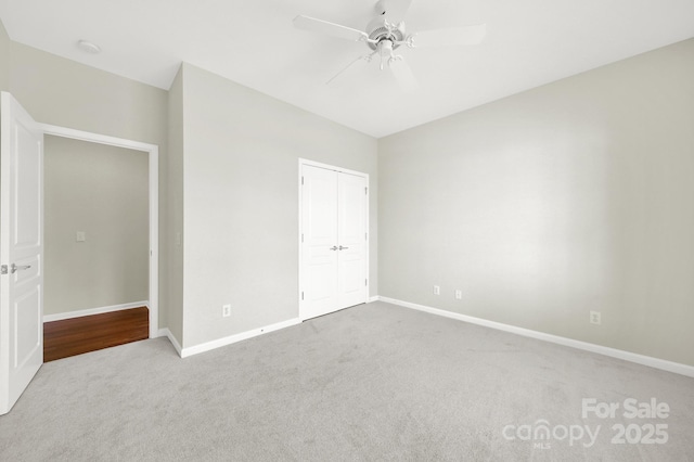 unfurnished bedroom with a closet, carpet flooring, a ceiling fan, and baseboards