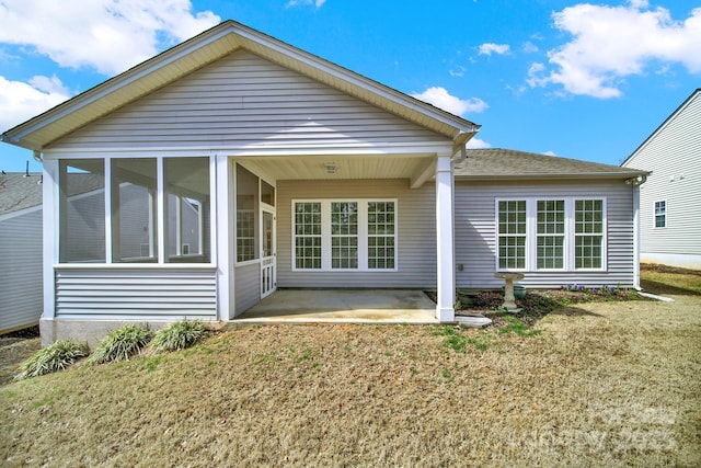 rear view of house featuring a patio area, a lawn, and a sunroom