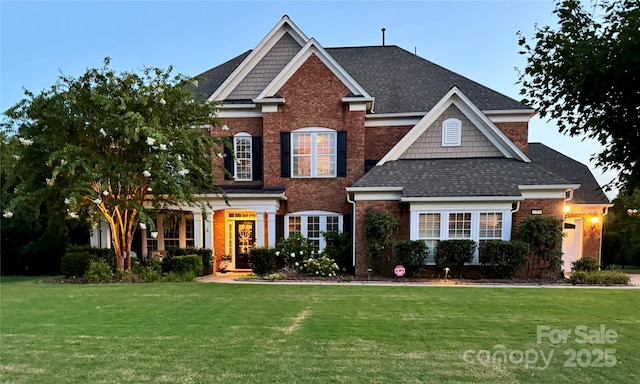 view of front of house featuring a front lawn, brick siding, and a shingled roof