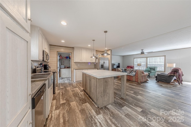 kitchen with a kitchen island, appliances with stainless steel finishes, open floor plan, and dark wood-style flooring