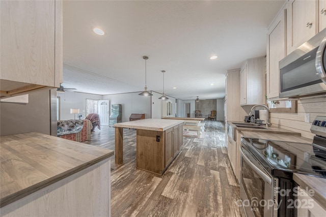 kitchen featuring a sink, dark wood-style floors, open floor plan, a center island, and appliances with stainless steel finishes