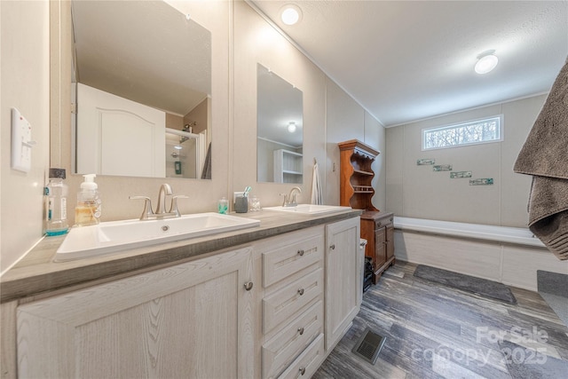 full bath with double vanity, wood finished floors, visible vents, and a sink