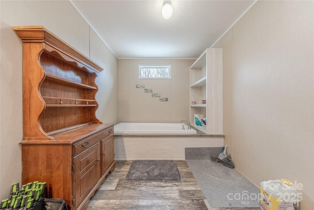 full bath with wood finished floors, a garden tub, and ornamental molding