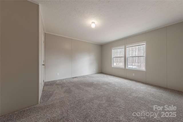 carpeted empty room with a textured ceiling