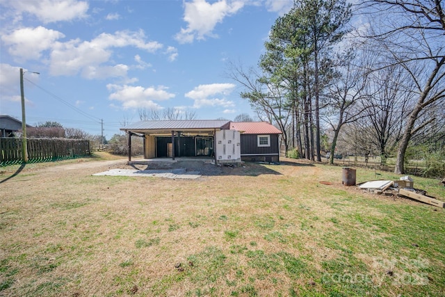 back of property featuring fence, metal roof, and a yard