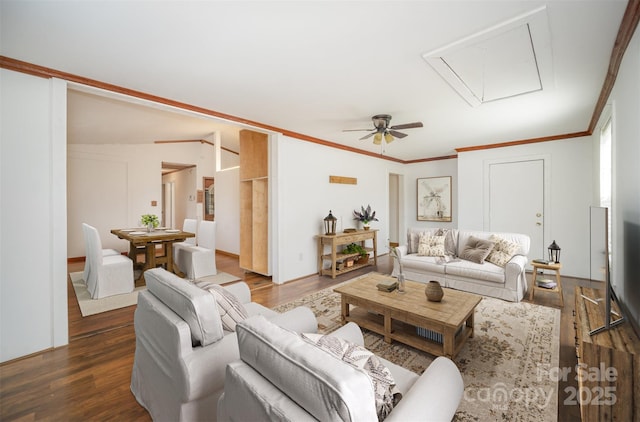 living area featuring attic access, crown molding, and dark wood-style flooring