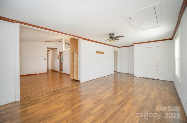 unfurnished living room featuring attic access, crown molding, and wood finished floors