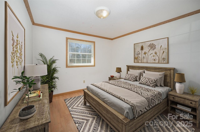 bedroom featuring crown molding, baseboards, and wood finished floors