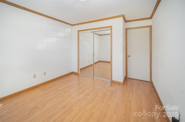 unfurnished bedroom with ornamental molding, a closet, light wood-style flooring, and baseboards