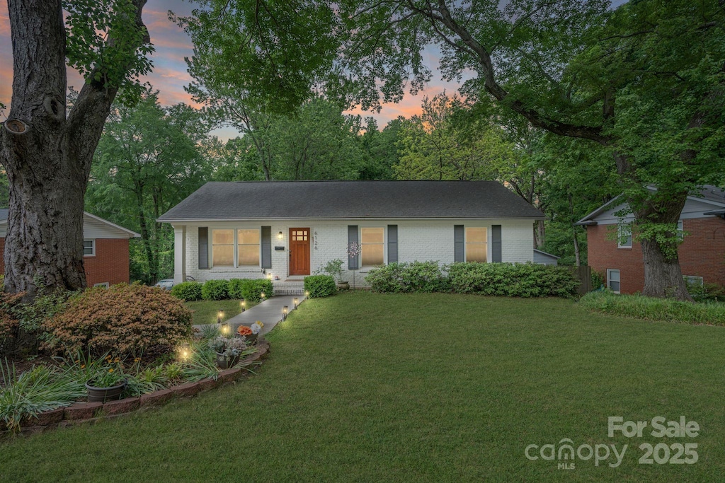 ranch-style house with a yard and brick siding