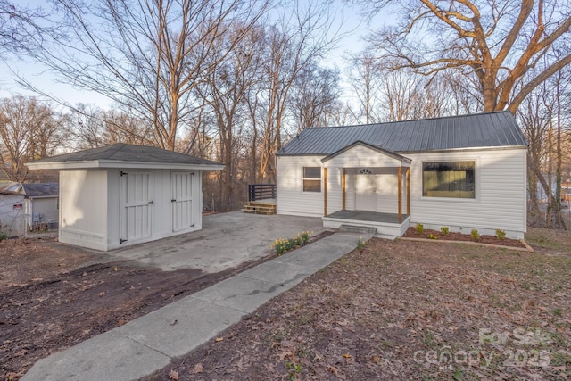 view of front of house featuring an outbuilding, metal roof, and a shed