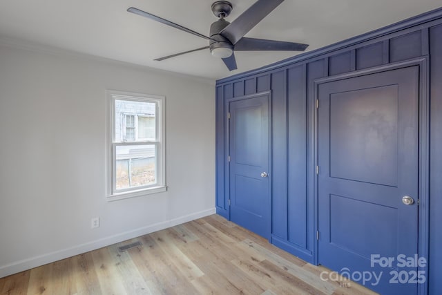 unfurnished bedroom with baseboards, light wood finished floors, visible vents, and crown molding