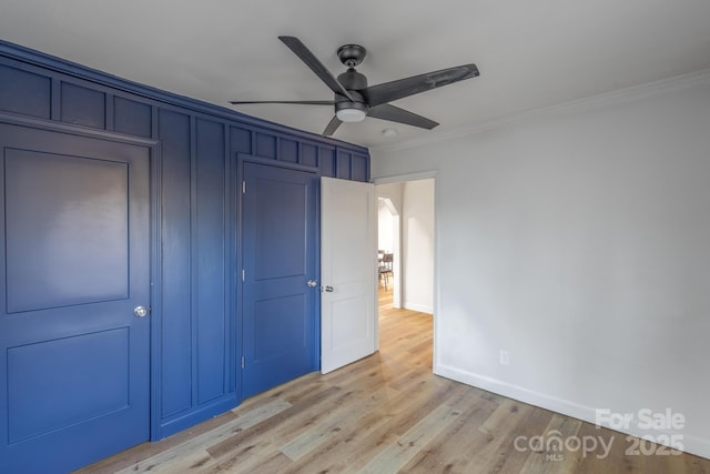 unfurnished bedroom featuring a ceiling fan, light wood-style flooring, ornamental molding, and baseboards