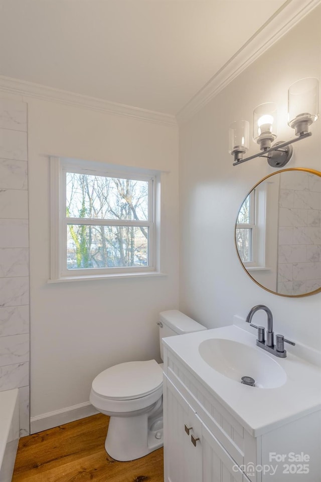 bathroom with baseboards, toilet, ornamental molding, wood finished floors, and vanity