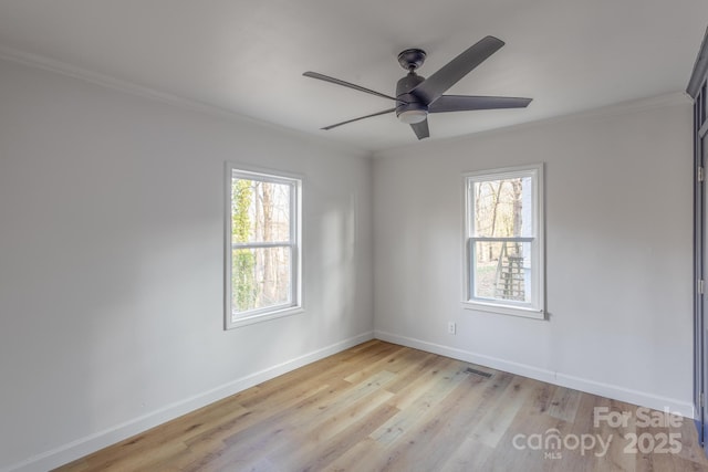 spare room featuring baseboards, ornamental molding, light wood finished floors, and a healthy amount of sunlight