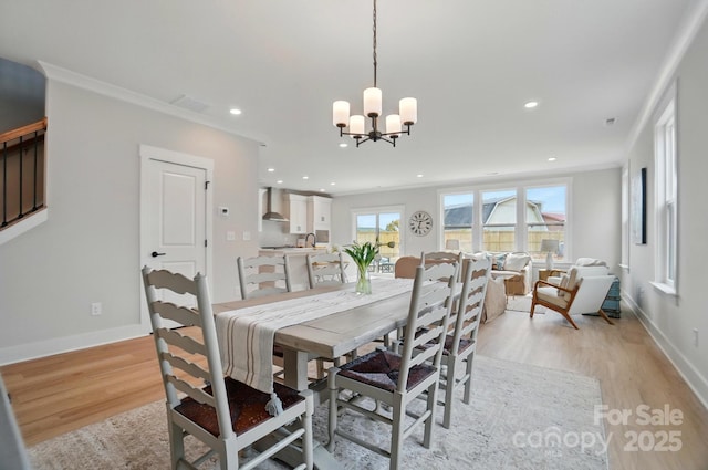 dining space featuring an inviting chandelier, ornamental molding, and light wood finished floors