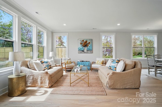 living area featuring crown molding, visible vents, plenty of natural light, and wood finished floors