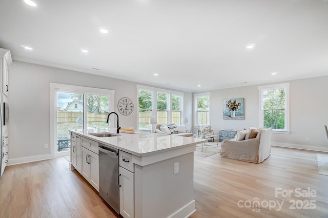 kitchen with a sink, light wood finished floors, dishwasher, and a healthy amount of sunlight