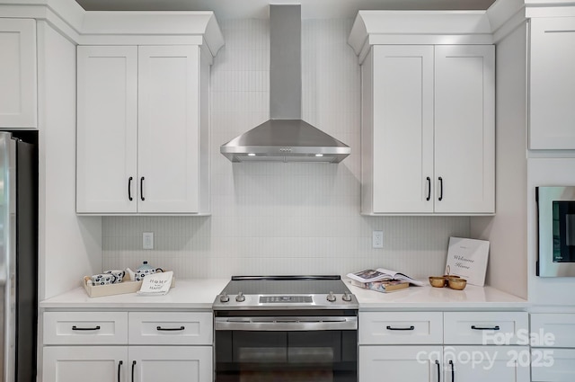 kitchen with wall chimney range hood, stainless steel appliances, white cabinets, and backsplash