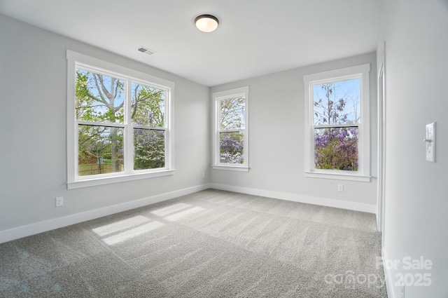 carpeted empty room with baseboards, plenty of natural light, and visible vents