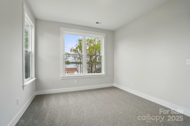 carpeted spare room featuring baseboards and visible vents