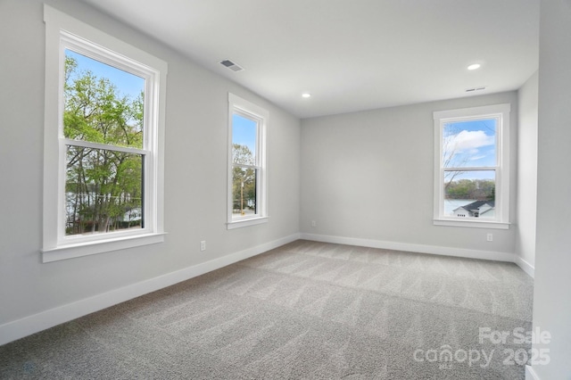 carpeted empty room featuring recessed lighting, baseboards, visible vents, and a wealth of natural light