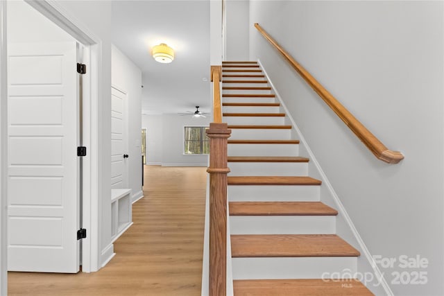 staircase featuring wood finished floors and baseboards