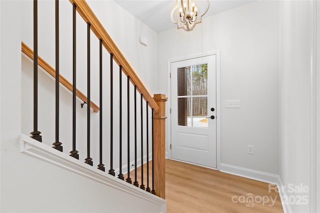 entryway featuring baseboards, stairway, a chandelier, and wood finished floors